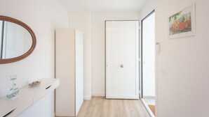 Una habitación moderna y minimalista con un armario blanco, un espejo y una puerta que da a otro espacio.