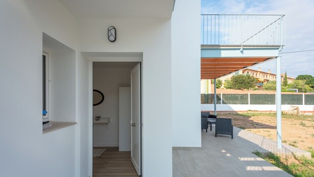 Un interior moderno con un pasillo que lleva a un balcón con vistas a un jardín.
