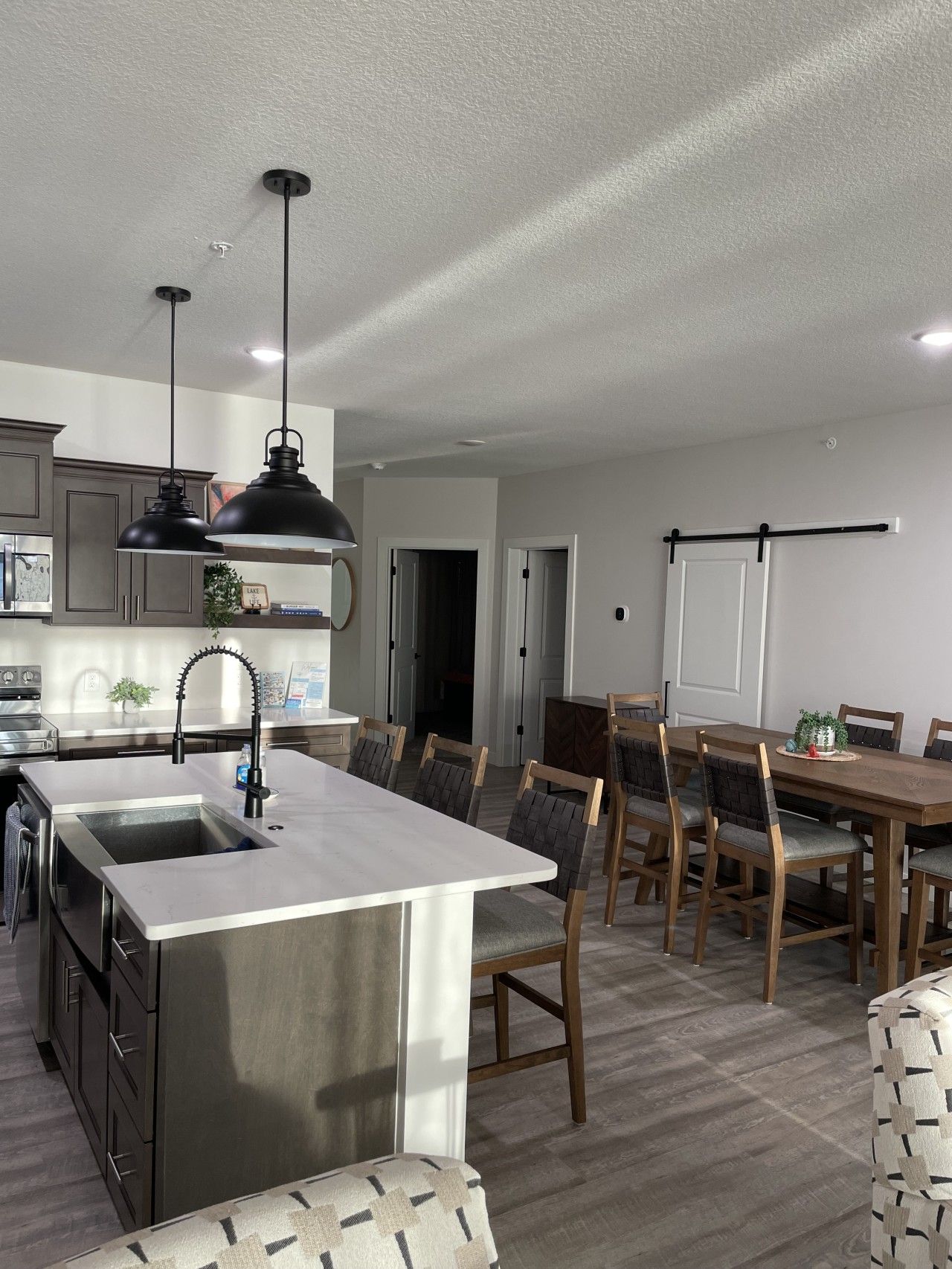 A modern kitchen with a central island, stainless steel appliances, and a dining area with wooden chairs and a table.