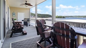 A covered outdoor area with a table and chairs, a grill, and a view of a lake. - Sierra Bay Sweet Retreat - Two Pools & More! (Camdenton)