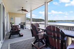 A covered outdoor area with a table and chairs, a grill, and a view of a lake. - Sierra Bay Sweet Retreat - Two Pools & More! (Camdenton)
