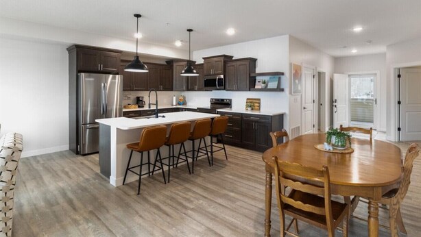 A modern kitchen with dark cabinets, stainless steel appliances, and a central island with bar stools. - Sierra Bay Sweet Retreat - Two Pools & More! (Camdenton)