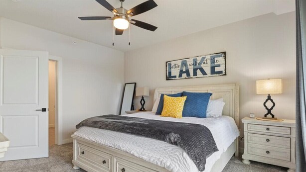A bedroom with a bed, bedside tables, a ceiling fan, and a wall sign. - Sierra Bay Sweet Retreat - Two Pools & More! (Camdenton)