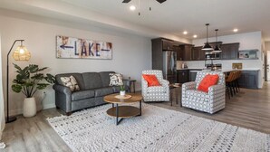A modern living room with a grey sofa, two patterned armchairs, a coffee table, and a large white rug. - Sierra Bay Sweet Retreat - Two Pools & More! (Camdenton)