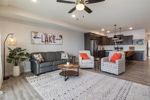 A modern living room with a grey sofa, two patterned armchairs, a coffee table, and a large white rug. - Sierra Bay Sweet Retreat - Two Pools & More! (Camdenton)