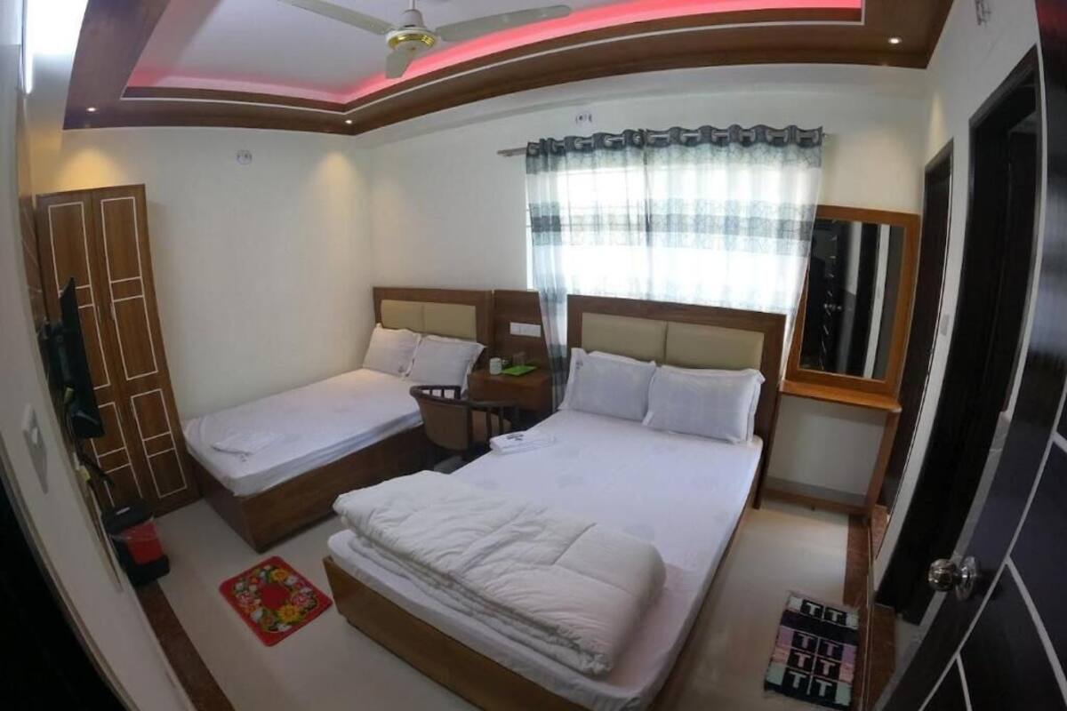 Une chambre avec deux lits, une armoire, une table de chevet, une commode et une fenêtre avec des rideaux.