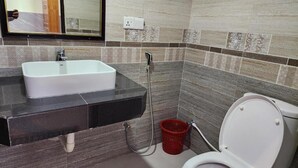 Une salle de bain avec un lavabo blanc, des toilettes et une douche.