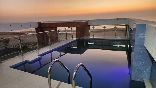 Une piscine sur le toit, dotée de rampes en verre et offrant une vue imprenable sur le coucher de soleil.
