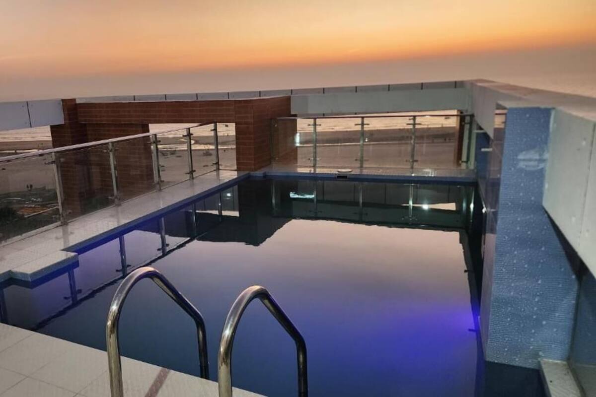Une piscine sur le toit, dotée de rampes en verre et offrant une vue imprenable sur le coucher de soleil.