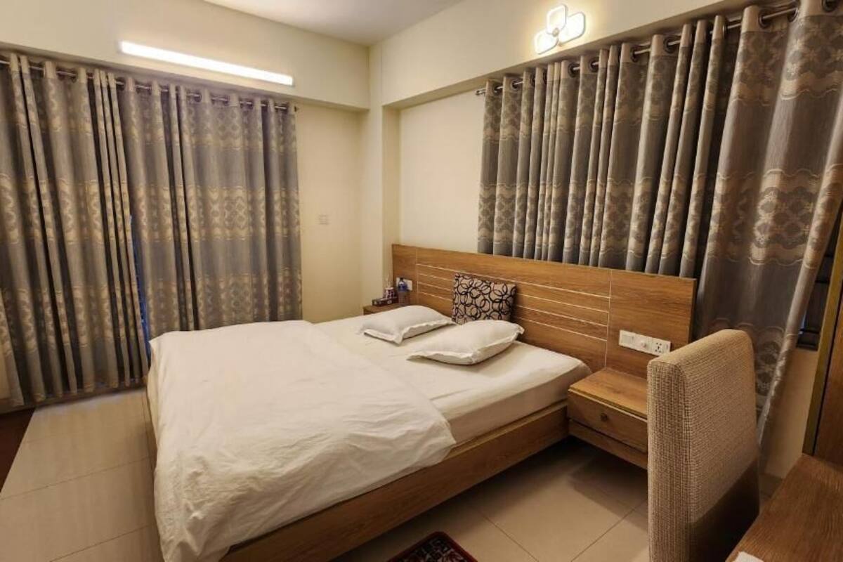 Une chambre à coucher avec un grand lit, une tête de lit en bois, deux tables de chevet et une chaise.
