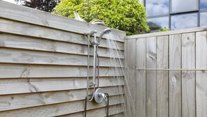A wooden fence with a metal showerhead attached to it. - Sundrenched 70's - Spa Pool + Sleep-out, Sleeps 11 (Rotorua)