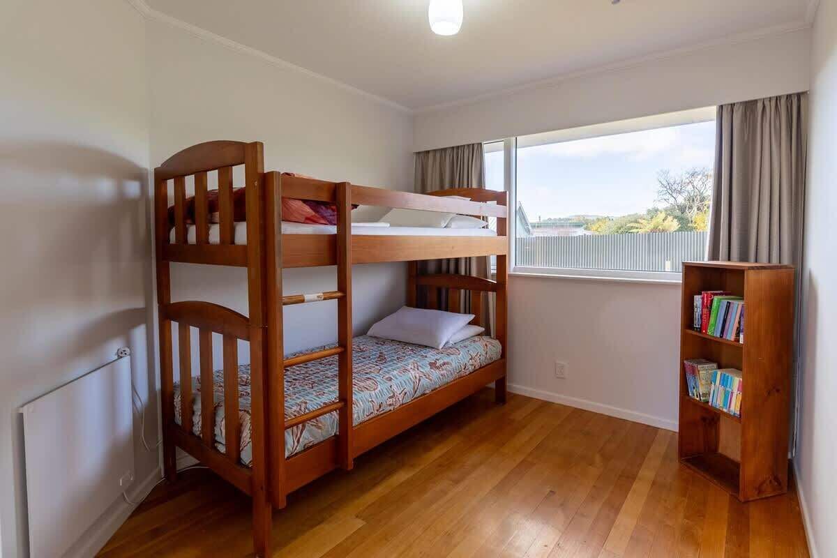 Une chambre avec un lit superposé, une fenêtre, un radiateur et une bibliothèque.