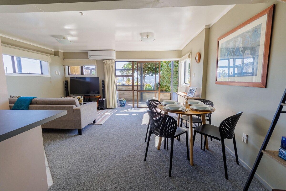 A modern living room with a sofa, TV, and dining area with chairs and a table.