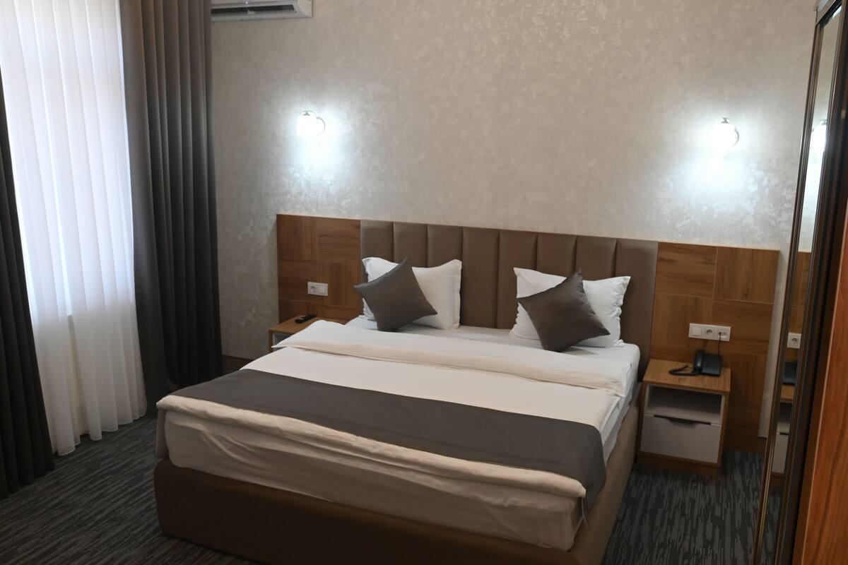 A hotel room with a large bed, two bedside tables, and a wooden headboard.