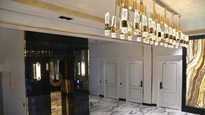 Un pasillo con piso de mármol, un candelabro y un espejo grande.