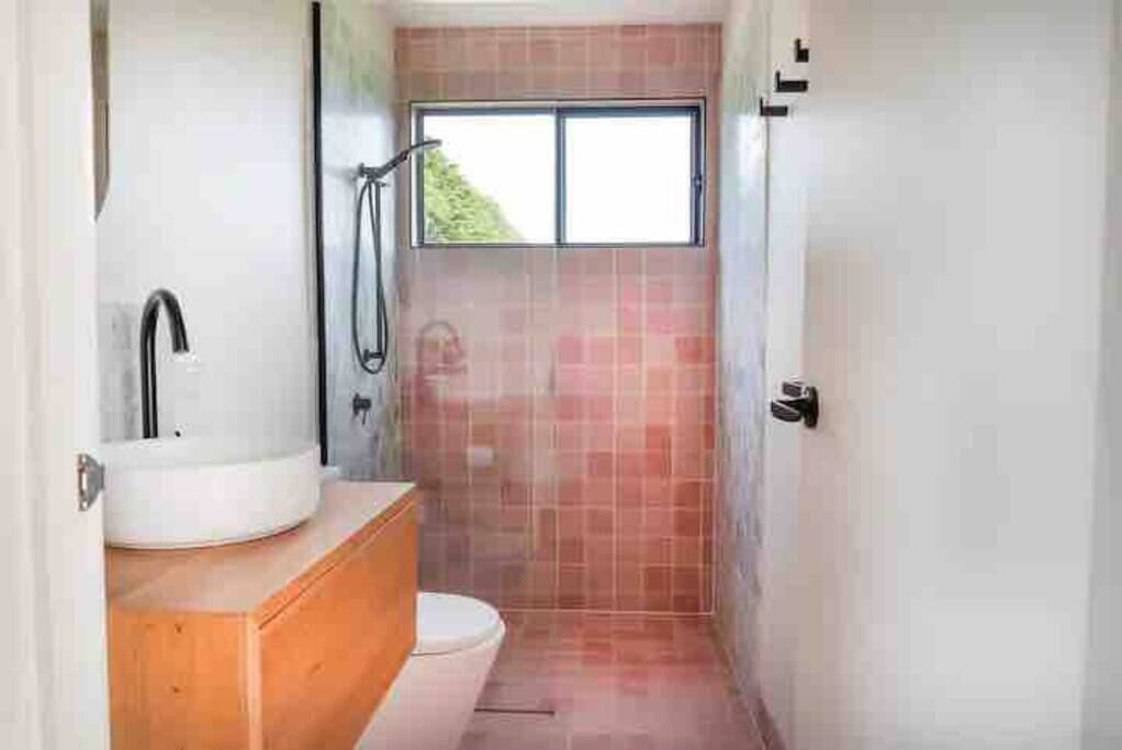 Ein kleines Badezimmer mit einem weißen Waschbecken, einer Holzwaschkommode und einer Duschkabine.