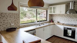 A modern kitchen with white cabinets, a large window, and a built-in oven.