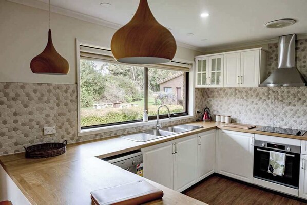 A modern kitchen with white cabinets, a large window, and a built-in oven.