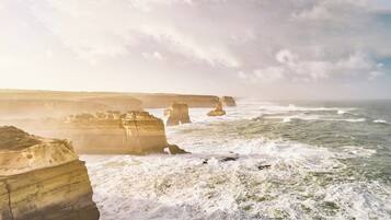 A coastal landscape with large rock formations and waves crashing against them.
