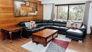 A modern living room with a sectional sofa, a wooden coffee table, and a large abstract painting on the wall.