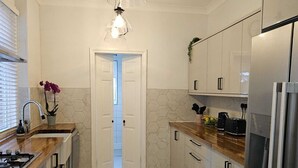 A modern kitchen with a wooden countertop, stainless steel appliances, and a view into the dining area. - Home Away from Home (Coventry)