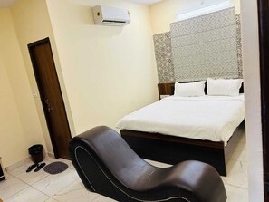 Une chambre à coucher comprenant un lit, une chaise, une porte et un appareil de climatisation.
