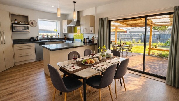 A modern kitchen with a dining area, large windows, and a patio.