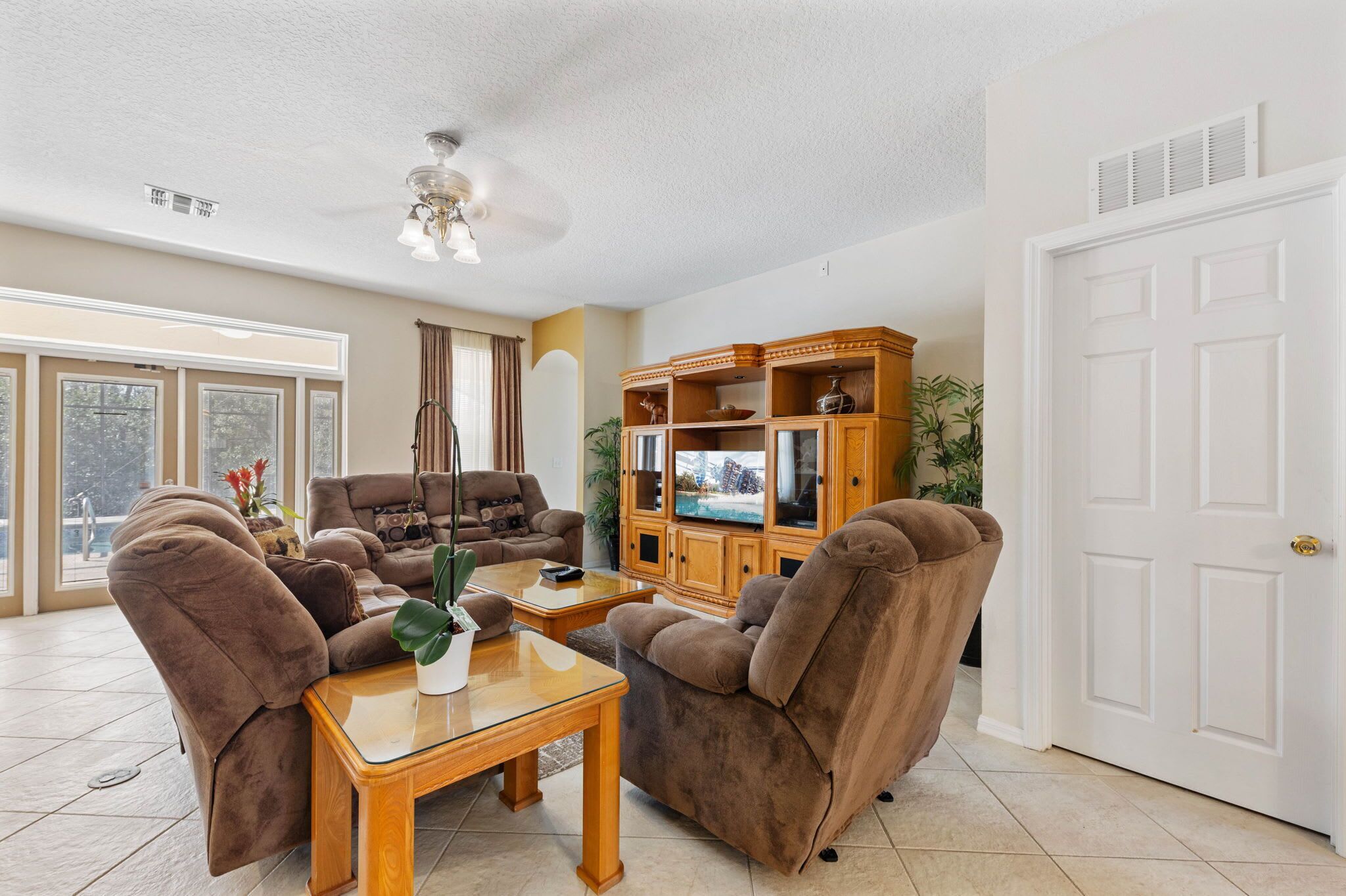 A living room with a sofa set, a wooden cabinet, and a ceiling fan.