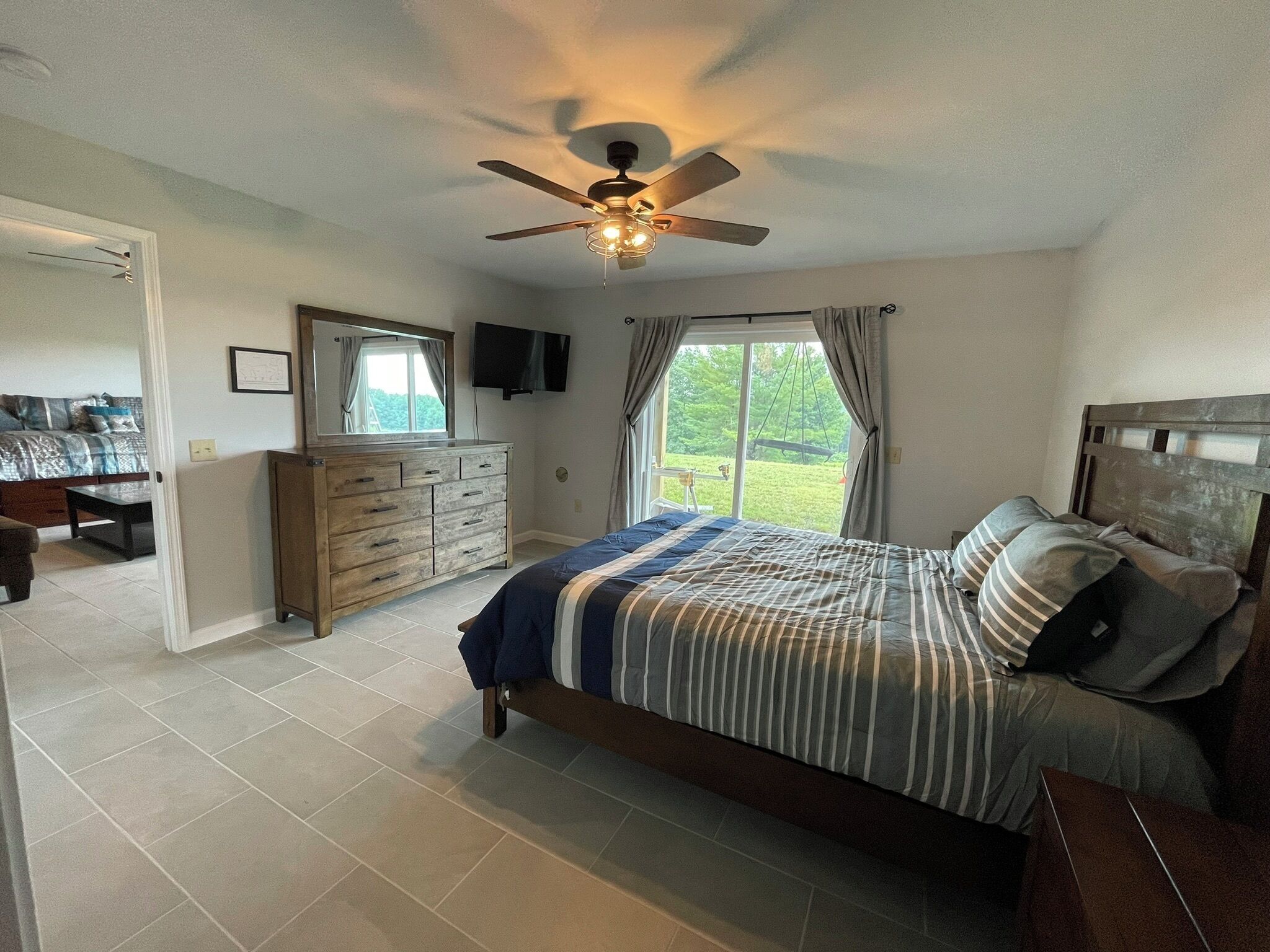 A bedroom with a bed, dresser, and a ceiling fan.