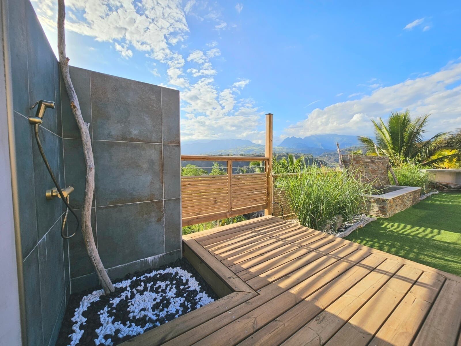 Une terrasse en bois offrant une vue sur les montagnes et un espace piscine avec une douche.