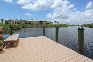 A wooden dock with a bench, leading to a water body with a building in the background. - LOVELY WATERFRONT BAY VILLAGE 2B/2B CONDO! WALK TO BEACH! (Fort Myers Beach)