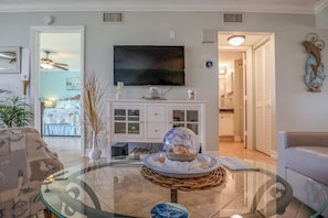 A living room with a glass coffee table, a television, and a decorative globe. - LOVELY WATERFRONT BAY VILLAGE 2B/2B CONDO! WALK TO BEACH! (Fort Myers Beach)