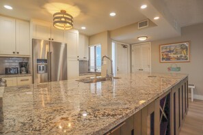 A modern kitchen with granite countertops, stainless steel appliances, and pendant lighting.