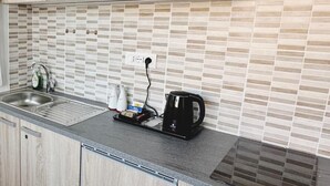 A kitchen with a tiled backsplash, a stainless steel sink, a coffee maker, and a kettle on the counter. - Rustico da Pina con Angolo Cottura (Castions)