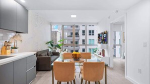 A modern kitchen with grey cabinets, a glass dining table, and a sofa.