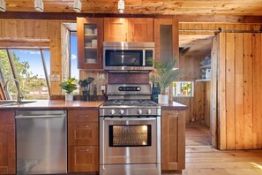 Una cocina moderna con electrodomésticos de acero inoxidable, armarios de madera y vistas al exterior.