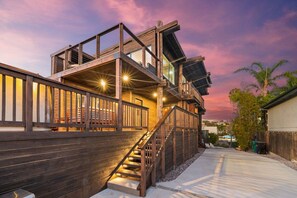 Une structure en bois à plusieurs niveaux, dotée d’un escalier menant à une terrasse supérieure, elle-même entourée d’une zone de terrasse agrémentée de rampes.