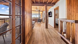 A wooden interior with a long hallway, a fireplace, and a view through large windows.