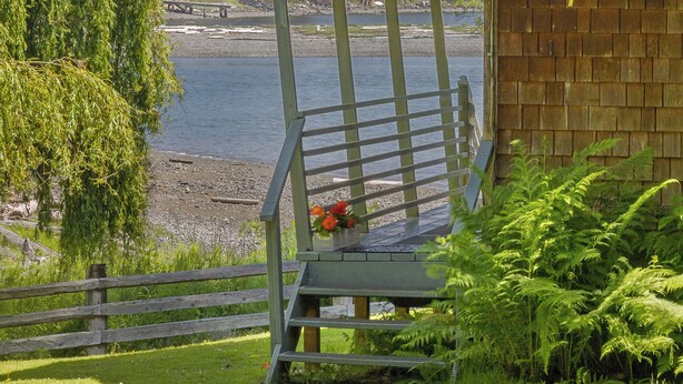 A wooden bench with a metal railing overlooking a body of water, a wooden fence, and a building with the number 107.