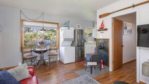 A compact living space with a kitchenette, a dining area, and a seating area with a red sofa and a grey rug.