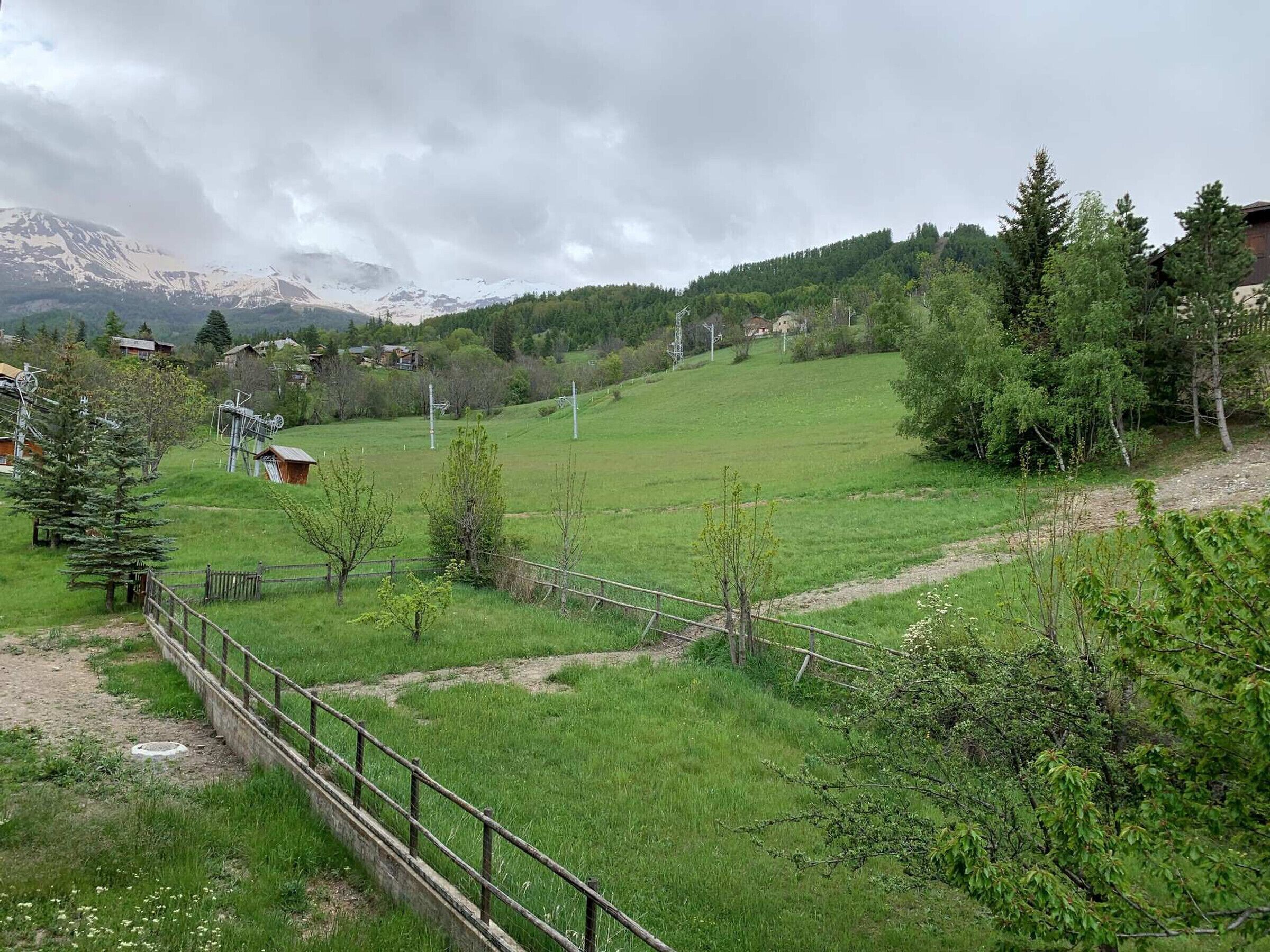 Un paisaje rural con un campo cubierto de césped, una valla de madera y una montaña al fondo.