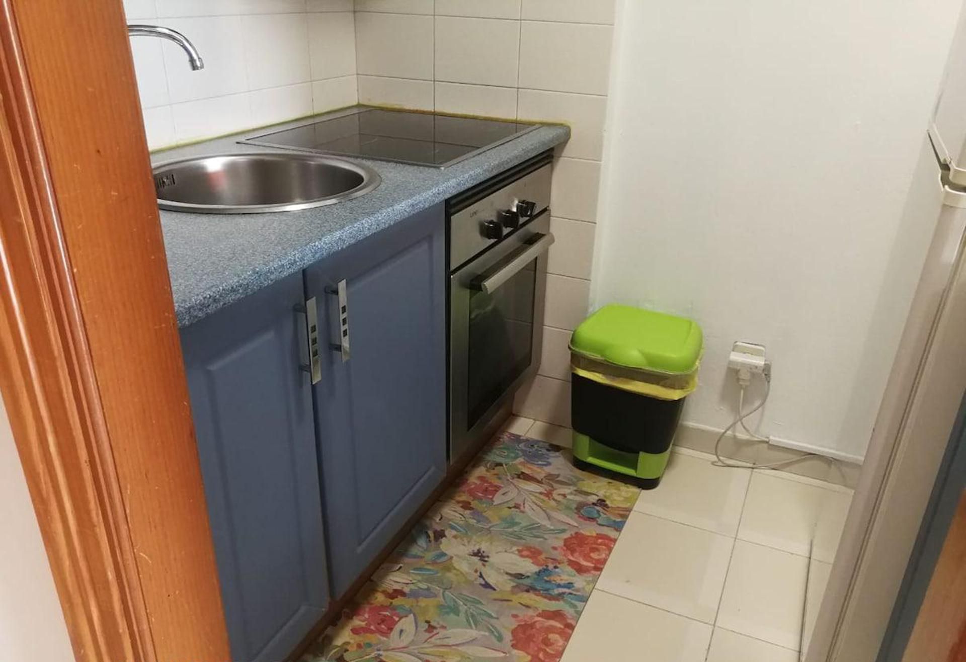 Une petite cuisine équipée d’un évier, d’une cuisinière et d’une poubelle.
