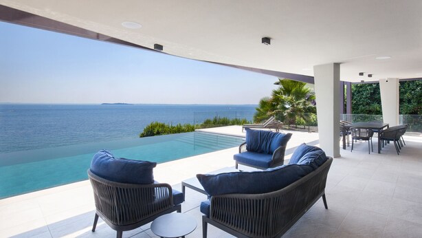 Ein moderner Außenbereich mit Sitzgelegenheit, Pool und Meerblick.