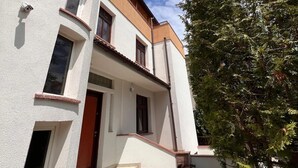 A two-story building with a white facade, multiple windows, and a staircase leading to the entrance. - Serenity Apartments and Studios (Eforie)