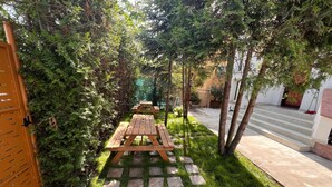 A garden with picnic tables and a concrete pathway. - Serenity Apartments and Studios (Eforie)