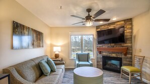 A living room with a sofa, armchair, round coffee table, fireplace, TV, and ceiling fan. - Partial Kitchen, King Bed, sleeps 4 (Mc Gaheysville)