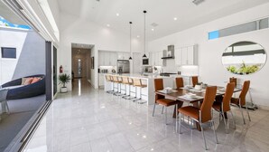 A modern kitchen with white cabinets, a central island with bar stools, and pendant lighting. - The Miralon Petite Oasis (Palm Springs)