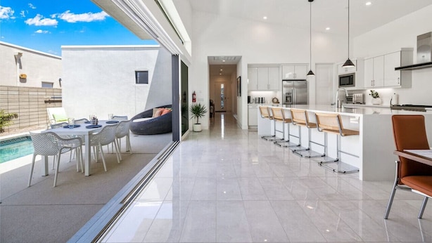 A modern kitchen with white cabinets, a central island, and pendant lighting. - The Miralon Petite Oasis (Palm Springs)