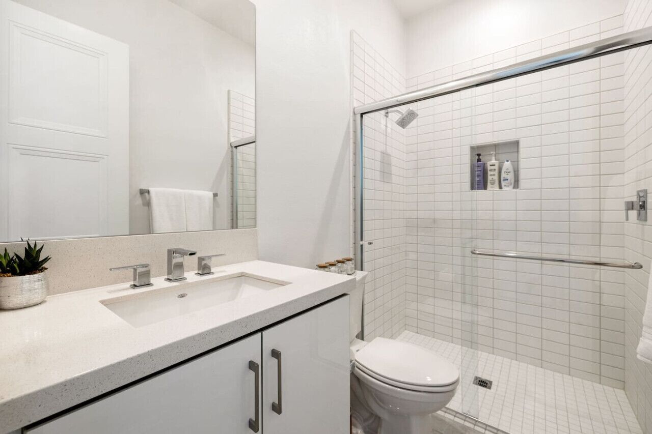 A modern bathroom with a white sink, mirror, and toilet.