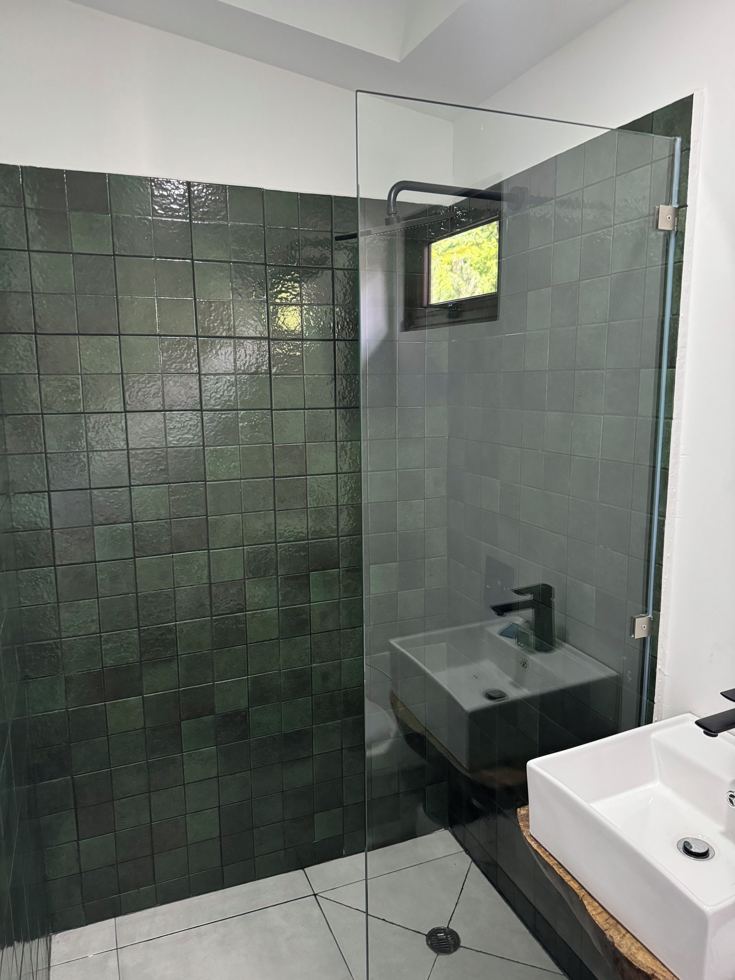 A modern bathroom with a glass shower enclosure, a white sink, and a large mirror.